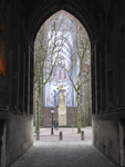 901084 Gezicht door de onderdoorgang van de Domtoren op het Verzetsmonument op het Domplein te Utrecht, met daarachter ...